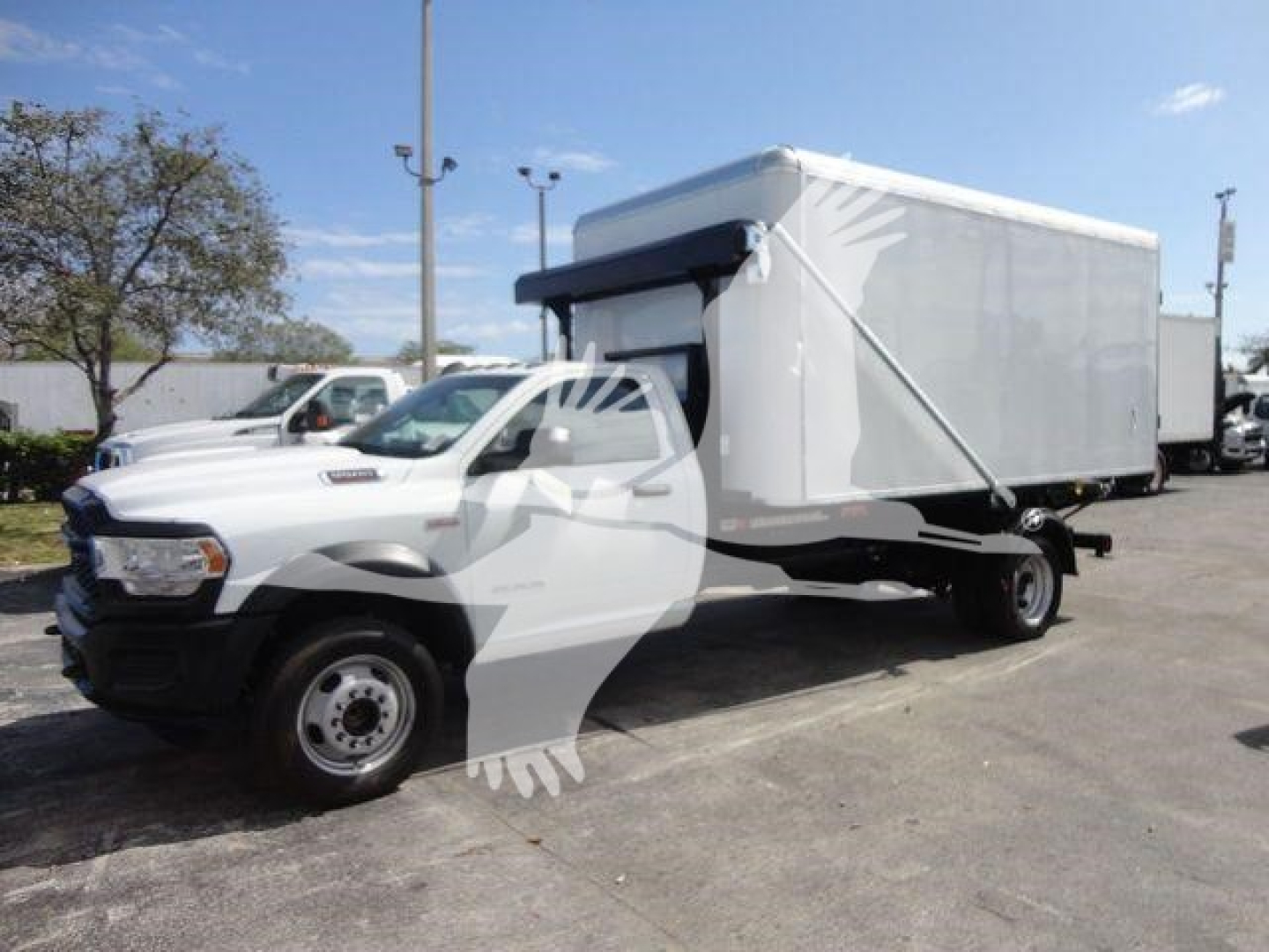 Ram 5500 HD roll-off truck with cargo box in side view showing front grille and cab, white exterior, no visible damage.