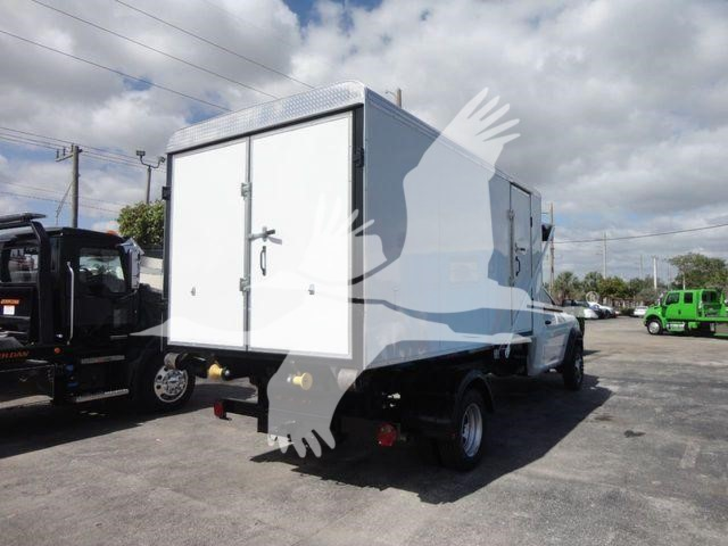 Ram 5500 roll-off truck with white rear doors and utility box, side view showing dual rear wheels and cargo compartments.