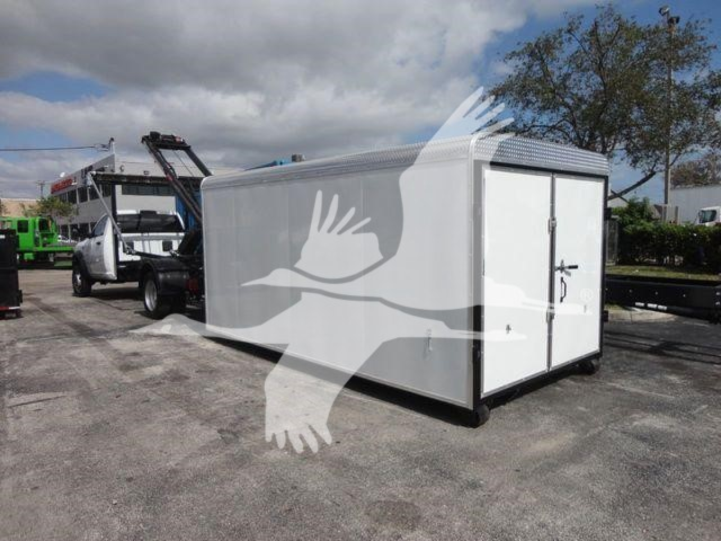 Ram 5500 HD rolloff truck with white enclosed cargo box and metal roof, side doors closed, in a lot.