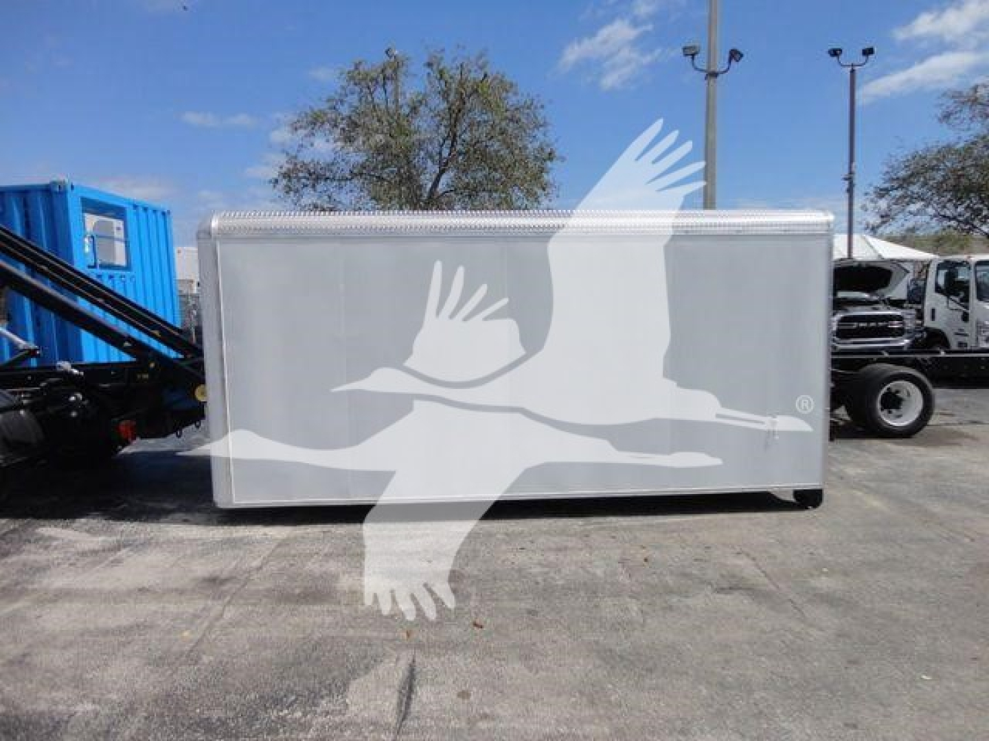 Ram 5500 HD roll-off truck with a silver box body and aluminum rail trim, parked in a lot.