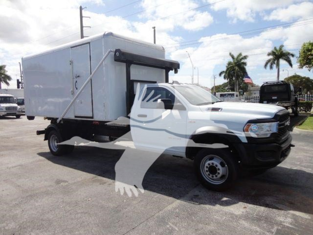 Ram 5500 HD roll-off truck showing a white cab and a large white utility box mounted on the chassis.