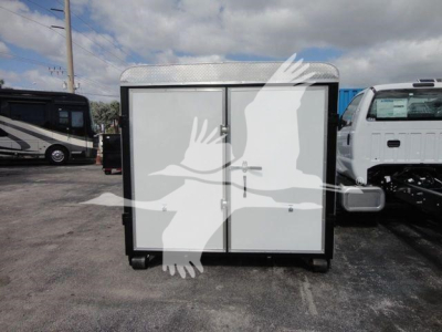 Ram 5500 HD roll-off truck with a front two-door storage cabinet in an open lot; visible text on truck not legible.
