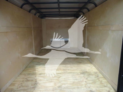 No obvious equipment visible; image shows empty truck trailer interior with wooden floor and sidewalls.