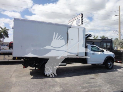 Ram 5500 HD roll-off truck with a large white service box mounted on the chassis, side view showing cargo box and cab, logo overlay not part of the image