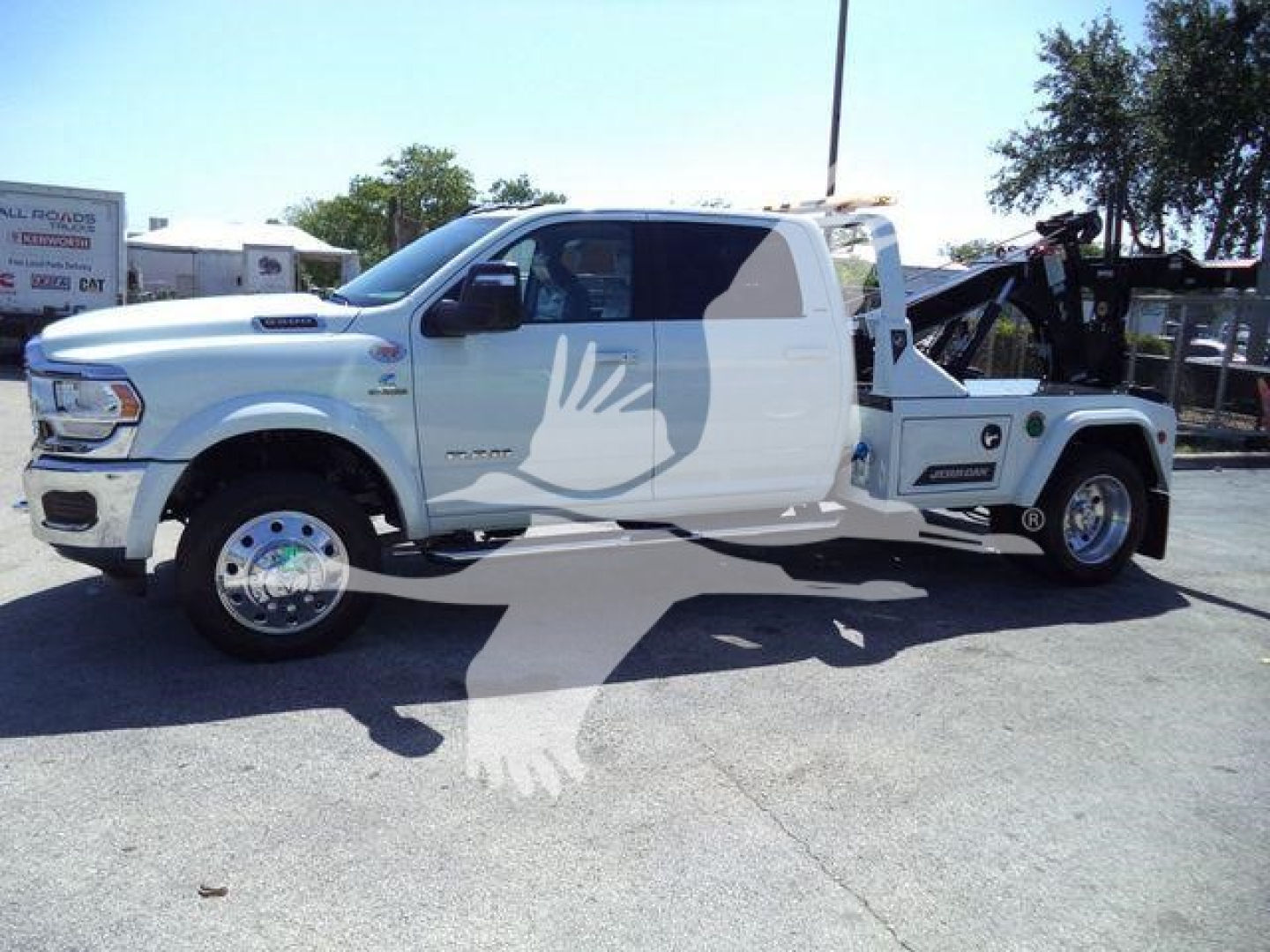 Ram 5500 Laramie tow truck side view showing winch and towing equipment, white crew cab with graphics, RAM badge visible.