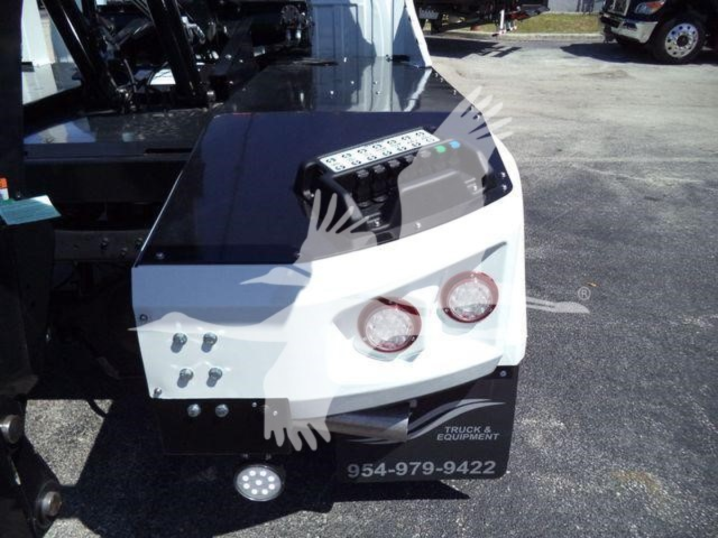 Ram 5500 winch-equipped front bumper area showing two round headlights, white and black bumper, control panel atop with various labeled buttons, and a metal winch housing.