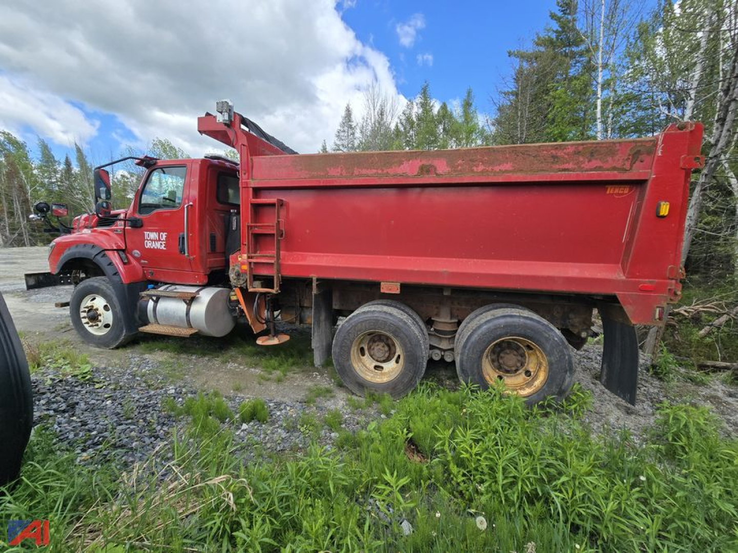 Red International HV613 dump truck side profile showing large red dumping bed and dual rear axles with mud tires.