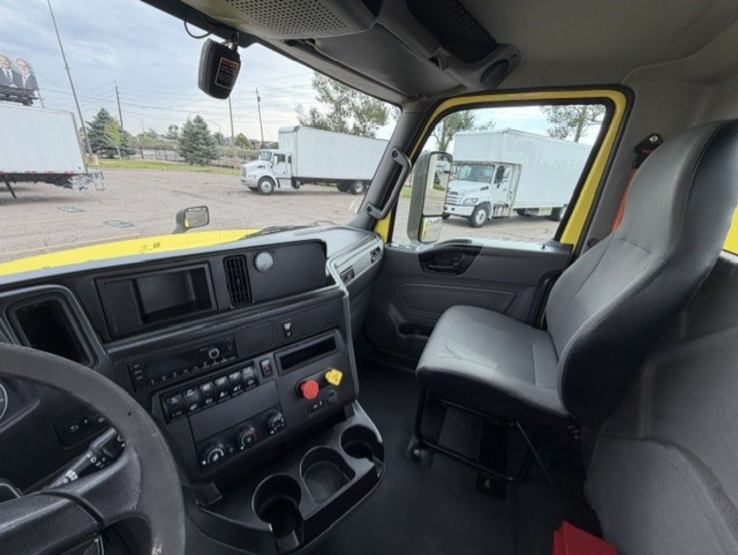 Cab interior of a 2023 International LT625 truck showing dashboard with controls, steering wheel, and yellow exterior visible through window.