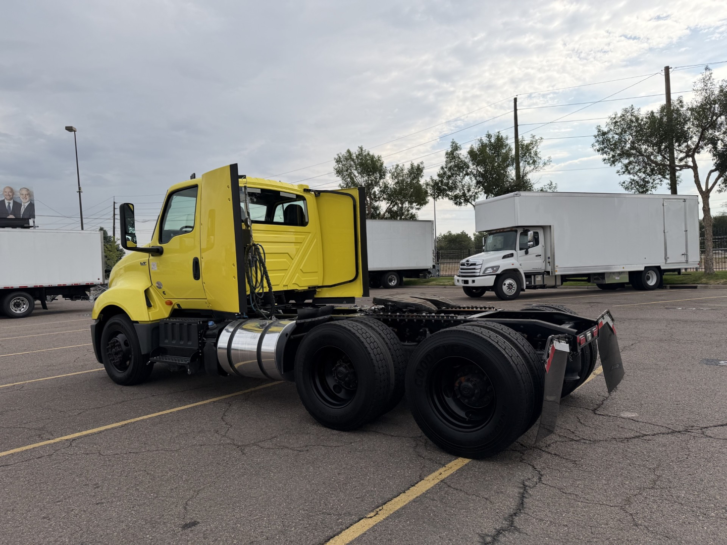 Image of a yellow International LT625 daycab tractor chassis in a parking lot, showing the cab, fuel tanks, and three rear axles with dual tires.