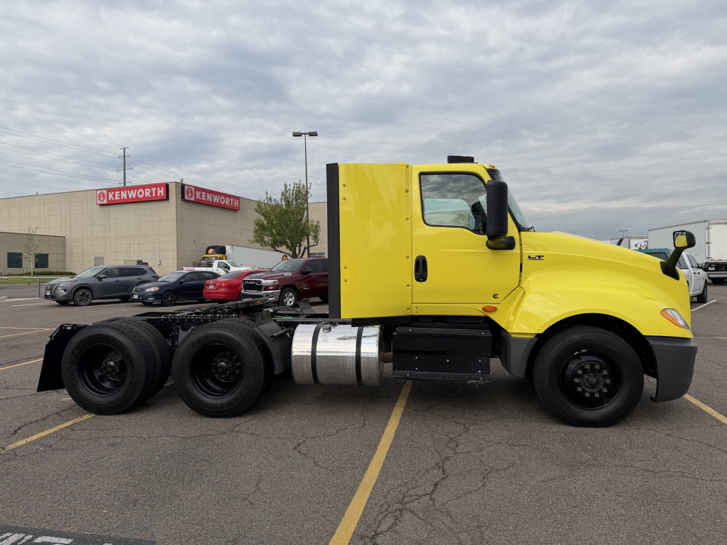 International LT625 truck side view showing cab, chassis, and dual rear axles in bright yellow, fuel tank, and side mirrors.