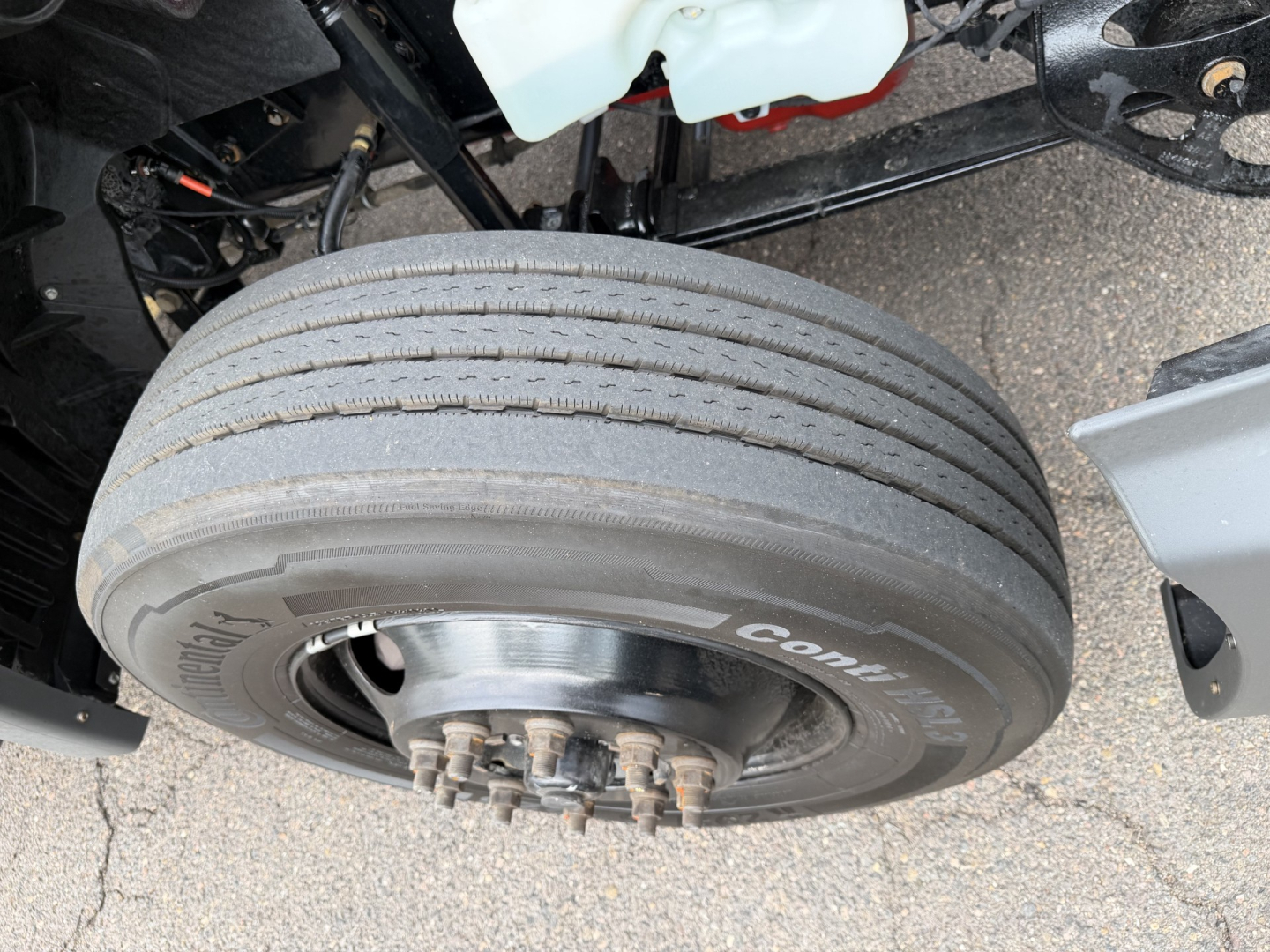 Wheel and tire assembly of a 2023 International LT625 truck showing front dual wheels and hub with lug nuts; part of the axle and brake components visible.