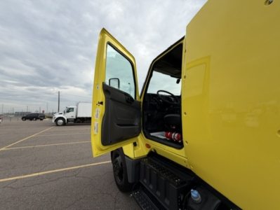 Truck cab showing open driver door and steps with yellow exterior and black interior.