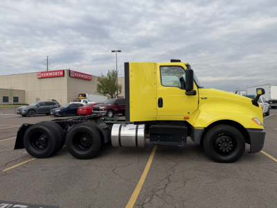 International LT625 truck side view showing cab, chassis, and dual rear axles in bright yellow, fuel tank, and side mirrors.