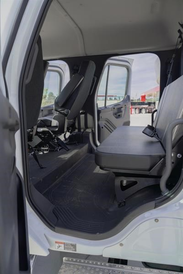 Cab and chassis interior view showing seating area in Freightliner truck cab with front bench seat and doorway, cargo area visible.