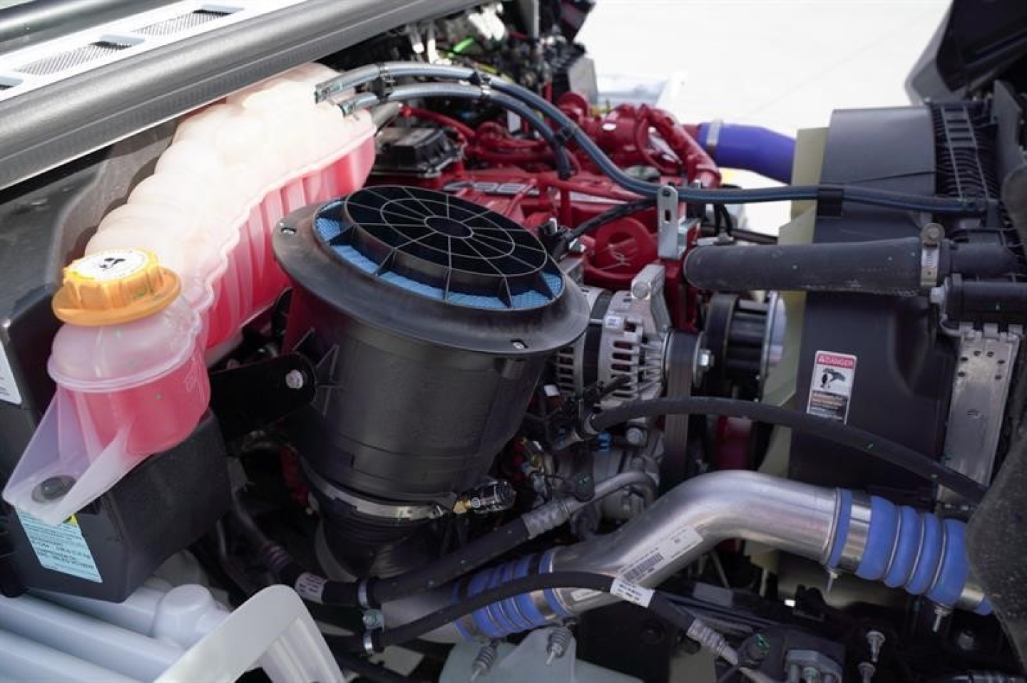 Freightliner M2 106 engine bay showing coolant reservoir, air intake, turbo piping, and various hoses.
