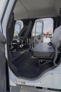 Cab and chassis interior view showing seating area in Freightliner truck cab with front bench seat and doorway, cargo area visible.