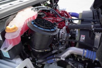 Freightliner M2 106 engine bay showing coolant reservoir, air intake, turbo piping, and various hoses.