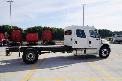 Freightliner M2 106 Plus cab and chassis in parking lot, side view, white cab with flatbed chassis and black frame