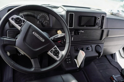 Cab and chassis interior showing steering wheel and dashboard of Freightliner M2 106 Plus with digital gauges and center touchscreen display.