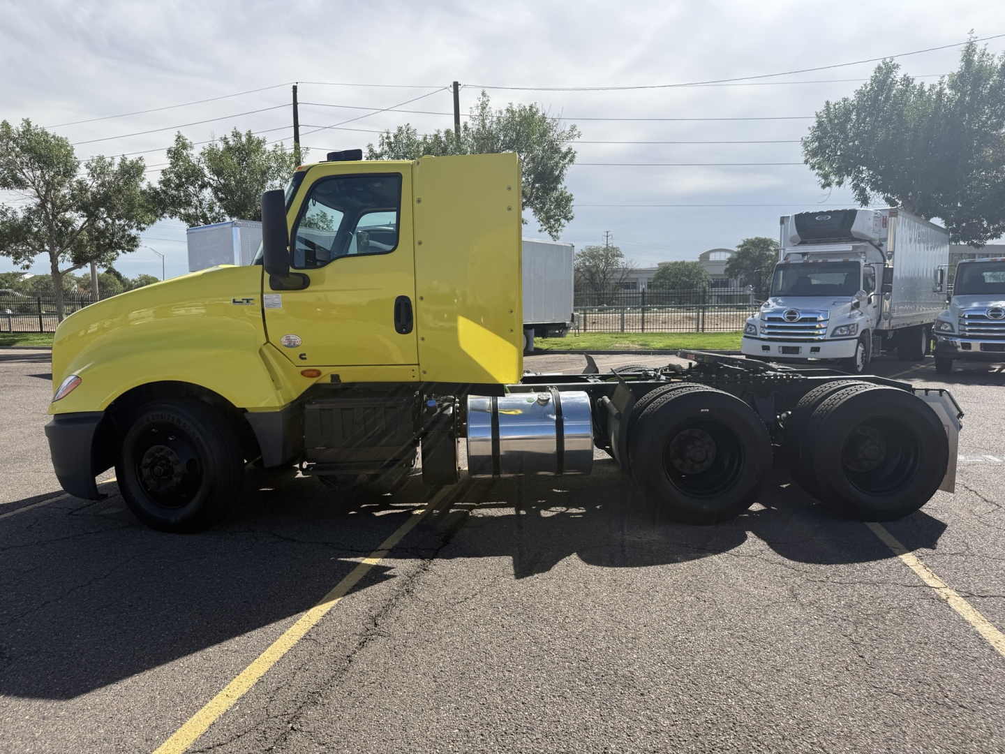 Truck cab of a bright yellow International LT625 conventional daycab side view showing chassis and rear axles.