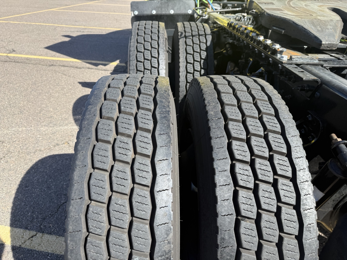 Dual rear axles and tires of a 2023 International LT625 truck with treaded dual tires visible and parts of the chassis.