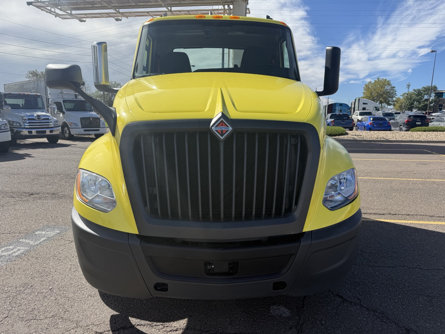 Front view of a yellow 2023 International LT625 conventional daycab truck with large black grille, black bumper, and tall side mirrors.