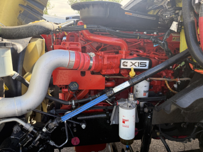 Truck engine bay with red engine labeled 6X13 and various hoses, filters visible
