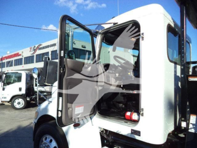 Peterbilt 337 rollback truck cab open with door ajar, interior seating and dashboard visible, truck parking lot background.