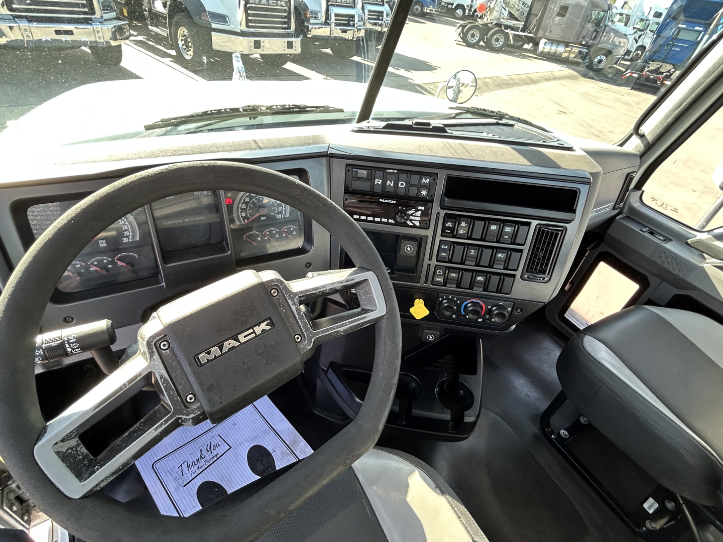 Mack PI64T truck interior showing steering wheel, dashboard, and center console with gauges and controls.