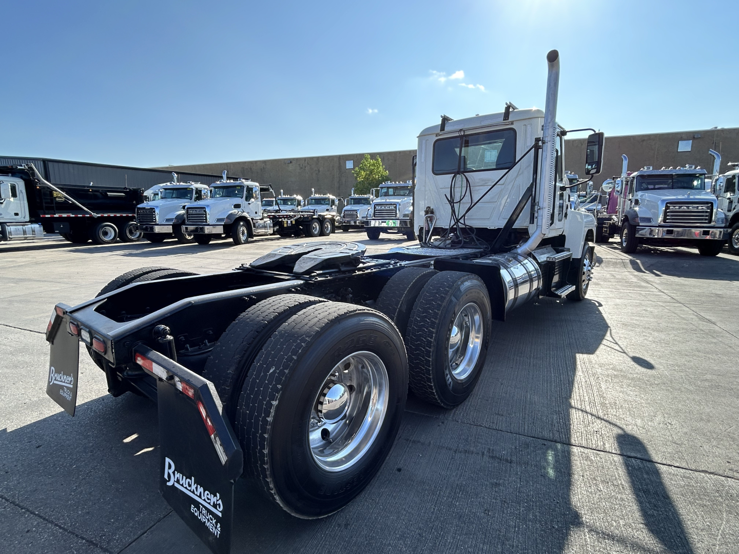 Mack PI64T tractor truck rear view showing dual rear axles and fuel tanks with chrome wheels.