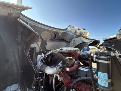 Mack PI64T engine bay showing exposed components, hoses, and red engine block under open cab area.