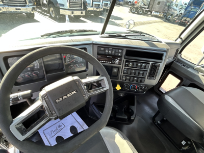 Mack PI64T truck interior showing steering wheel, dashboard, and center console with gauges and controls.