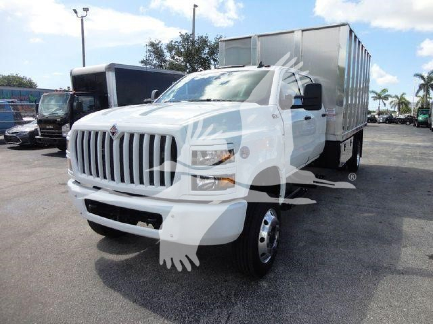Truck: 2023 International CV dump truck with white cab and silver cargo bed, front grille with vertical slats, side mirrors, large headlights, parked in a lot.