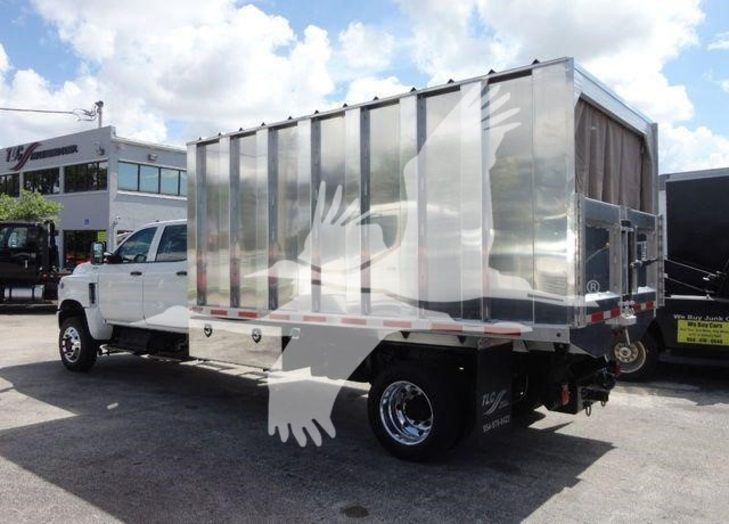 Dump truck with aluminum dump body on International CV series, side view showing rear wheels and reflective surface