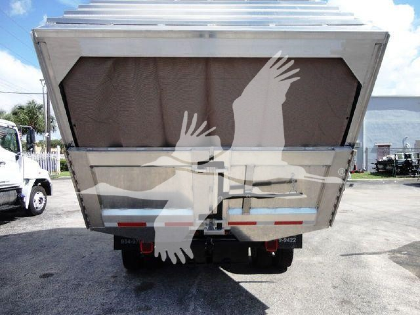 Dump truck bed with hydraulic tailgate in raised position and rear view showing bumper reflectors and rear lights.