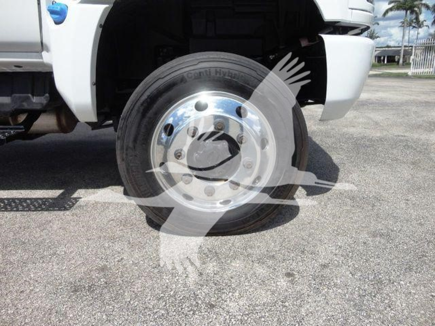 Front left wheel of a truck with chrome hubcap, fender visible; faint watermark; no legible model text.