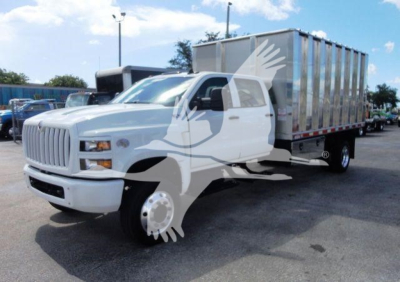 International CV dump truck showing white cab and a large aluminum cargo bed with side rails, side view in a dealership lot.