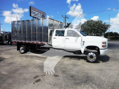 Truck cab and dump bed from a 2023 International CV, white cab with a large metallic dumping box, side view.