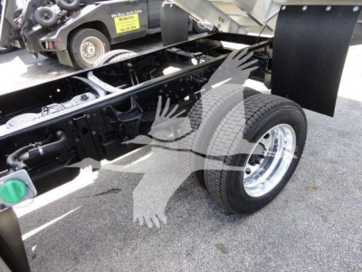 International CV dump truck chassis showing rear wheel and frame with stickered components and a spare tire area.