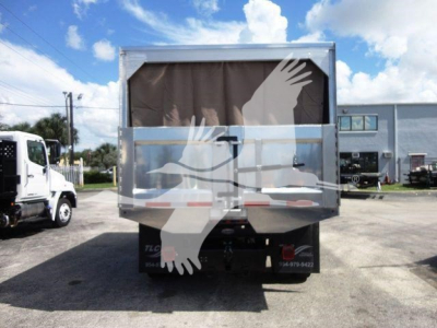 Dump truck rear view showing tarp-covered bed and chassis with tail lights and bumper.