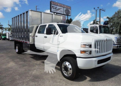 Dump truck from side angle with white cab and silver cargo bed, International CV series, new truck in lot.