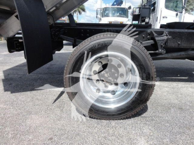 Wheel and tire along with chassis components of a new 2023 International CV dump truck showing the front wheel and suspension.