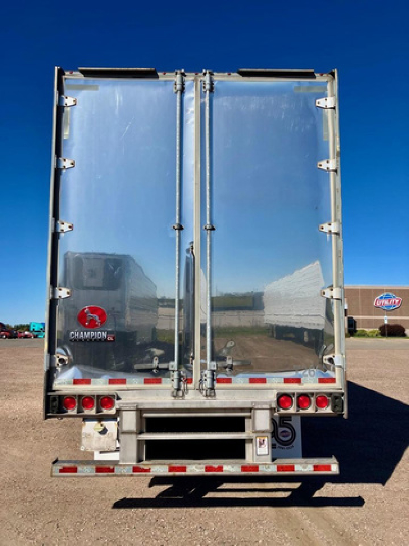 Rear view of a blue 2020 Great Dane dry van trailer showing twin rear doors with hinges and latches, Champion logo on left door, reflection of surroundings.