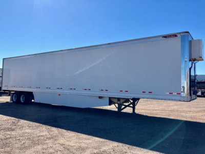Great Dane dry van trailer in profile view with white exterior and dual rear axles, landing gear visible, under blue sky.