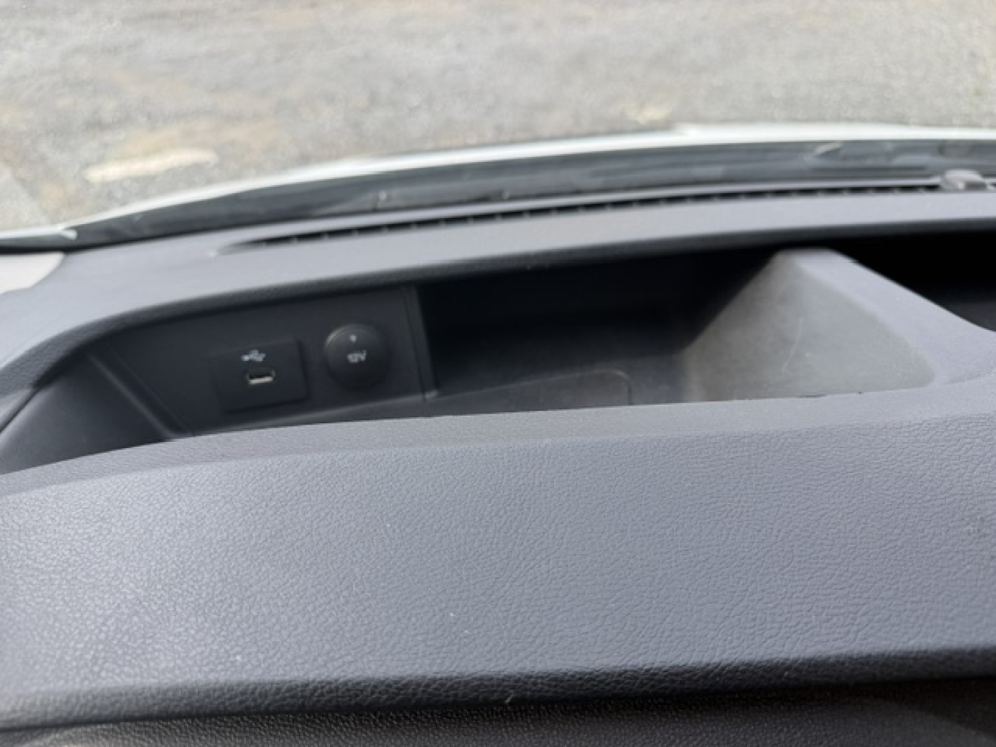 Interior view of Ford Transit 250 dashboard area showing USB/aux ports and blank storage, wipers and hood edge visible through windshield.