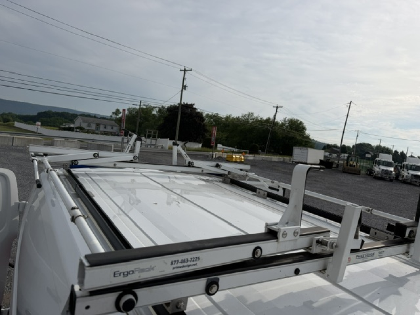 Truck bed rack system on a white Ford TRAN250 service utility truck showing ErgoRack label and rails.