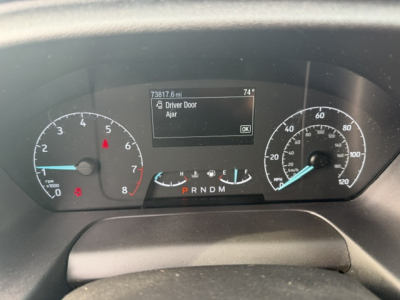 Dashboard of a 2021 Ford TRAN250 showing instrument cluster with speedometer and tachometer, center display reading 73817.6 mi and 74° outside, gear selector PRNDM, and warning icons.
