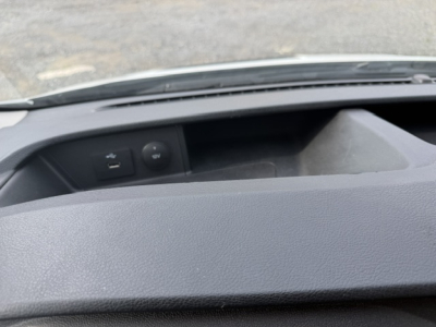 Interior view of Ford Transit 250 dashboard area showing USB/aux ports and blank storage, wipers and hood edge visible through windshield.
