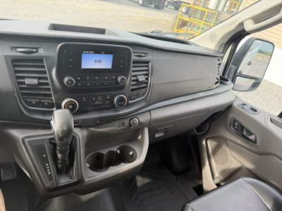Ford Transit 250 interior dashboard and center console showing gear shifter, cup holders, and controls.