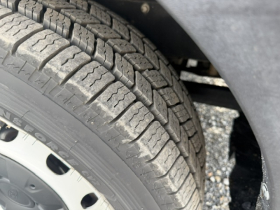 Tire tread and wheel well view from a Ford TRAN250 truck showing all-season tire with visible tread pattern.